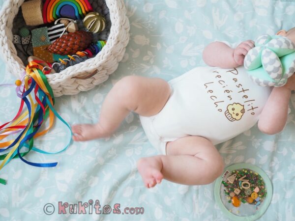 Un bebe jugando con la pelota Montessori y el cesto de los tesoros